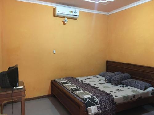 een slaapkamer met een bed, een bureau en een televisie bij Hotel Alami in Klaten