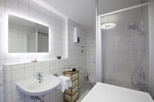 La salle de bains blanche est pourvue d'un lavabo et d'une douche. dans l'établissement City Center Apartments, à Kirchheim unter Teck