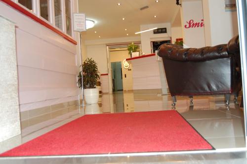 a lobby with a red carpet and a leather chair at Hotel Friesengeist in Wiesmoor