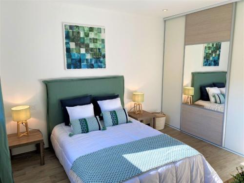 a bedroom with a green bed with pillows and a mirror at Villa Coconing à 7min des plages - Piscine chauffée - Clim - BBQ - Parking privatif - Fibre in Porto-Vecchio