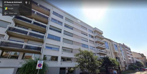 un grand bâtiment blanc avec des fenêtres donnant sur une rue dans l'établissement Appartement Mozart, à Strasbourg