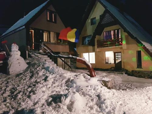 una pila de nieve delante de una casa en Pensiunea Pusu, en Ranca