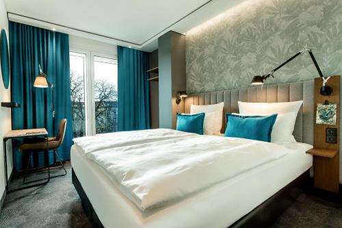 a bedroom with a large white bed with blue accents at Motel One Bonn-Hauptbahnhof in Bonn