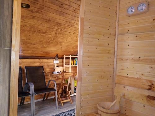 Zimmer mit einer Holzwand mit einem Stuhl und einem Tisch in der Unterkunft Pensiunea Verde in Baia Sprie