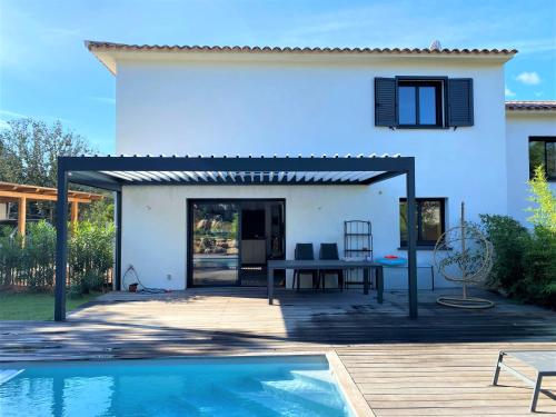 une terrasse avec une table et une piscine en face d'une maison dans l'établissement Villa Coconing à 7min des plages - Piscine chauffée - Clim - BBQ - Parking privatif - Fibre, à Porto-Vecchio