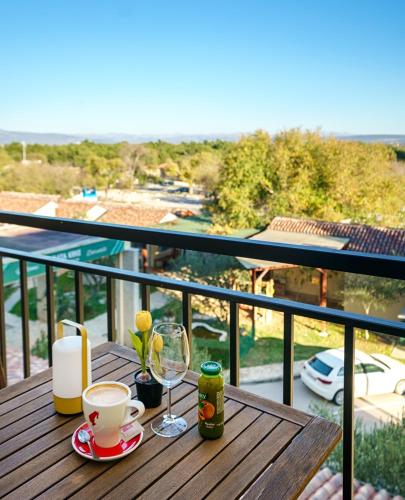 a wooden table with a drink and glasses on a balcony at Hotel Vrata Krke in Lozovac
