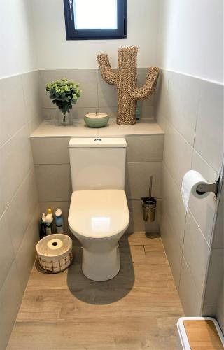 La salle de bains est pourvue de toilettes et d'un vase de fleurs. dans l'établissement Villa Coconing à 7min des plages - Piscine chauffée - Clim - BBQ - Parking privatif - Fibre, à Porto-Vecchio