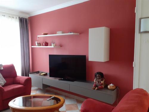 een woonkamer met een flatscreen-tv aan een rode muur bij Chambre confortable Saint Venant in Saint-Venant