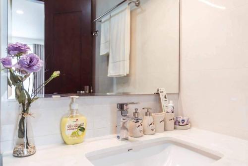 - un lavabo avec un vase de fleurs et un miroir dans l'établissement VINATA 289 Khuất Duy Tiến, à Hanoï