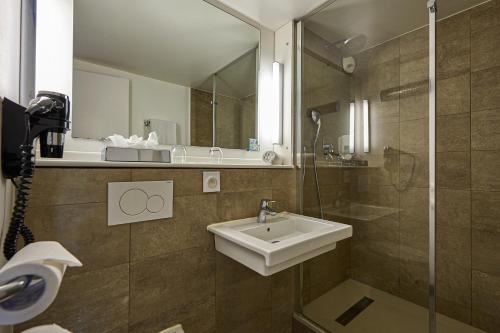 a bathroom with a sink and a mirror at Kyriad Bordeaux - Merignac Aéroport in Mérignac