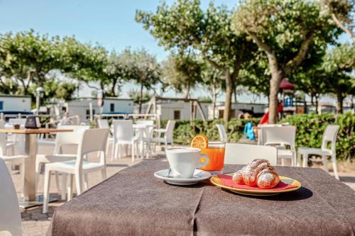 a table with a cup of coffee and pastries on it at Miramare Camping Village in Sottomarina