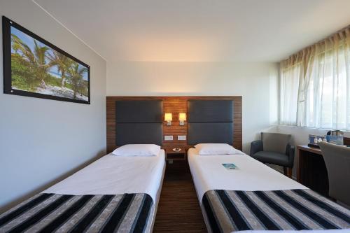 a hospital room with two beds and a desk at Kyriad Bordeaux - Merignac Aéroport in Mérignac