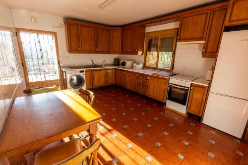 a kitchen with wooden cabinets and a table and a refrigerator at Casa Rural El Abeto in Torre de Don Miguel