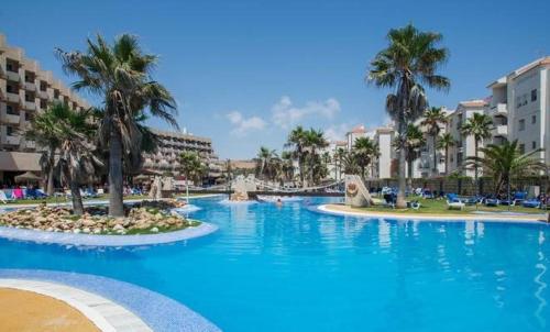 a large swimming pool with palm trees and buildings at AR Almerimar in Almerimar