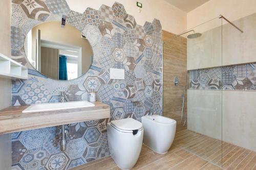 Un baño con lavabo, inodoro y espejo. en Villa San Teodoro by BarbarHouse, en San Pietro in Bevagna