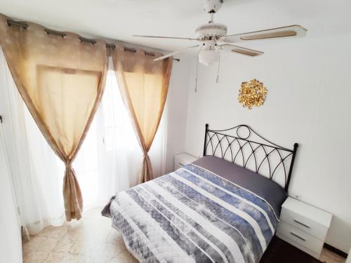 een slaapkamer met een bed en een plafondventilator bij Sunny apartment near the beach in Santa Pola