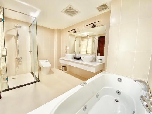 a bathroom with a tub and a toilet and a sink at Elephants Hotel in Buon Ma Thuot