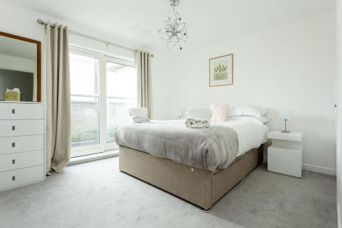 een witte slaapkamer met een bed en een raam bij Beach Point in Poole