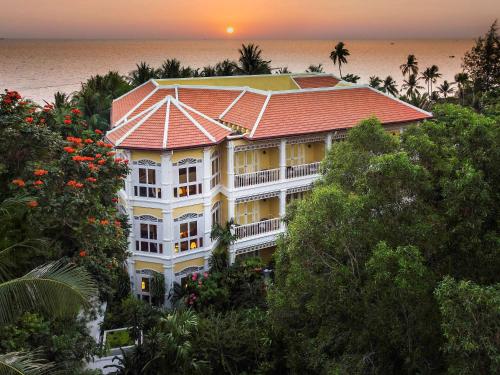 ein großes weißes Gebäude mit rotem Dach am Meer in der Unterkunft La Veranda Resort Phu Quoc - MGallery in Phu Quoc