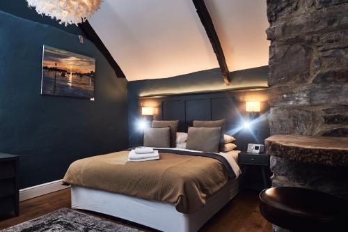 a bedroom with a large bed and a stone wall at The Brown's Hotel in Laugharne