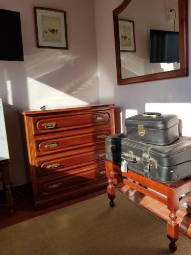 a room with a dresser and luggage on a table at Pensão David, B&B in São Pedro do Sul