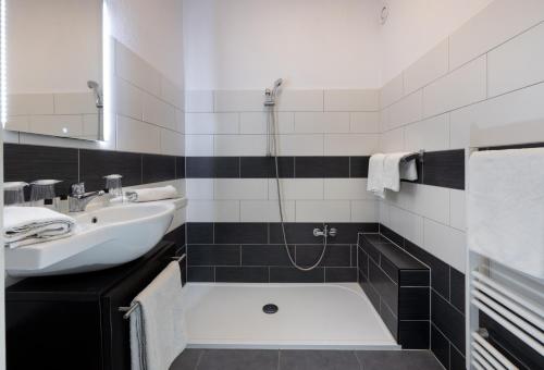 a black and white bathroom with a sink and a shower at The Originals City, Hôtel Galaxie, Nice Aéroport in Saint-Laurent-du-Var