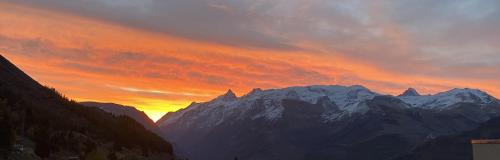 a sunset over a mountain range with snow covered mountains at Hotel Le Beau Site in Auris
