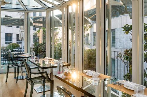 a restaurant with glass tables and chairs and windows at The Street Milano Duomo | a Design Boutique Hotel in Milan