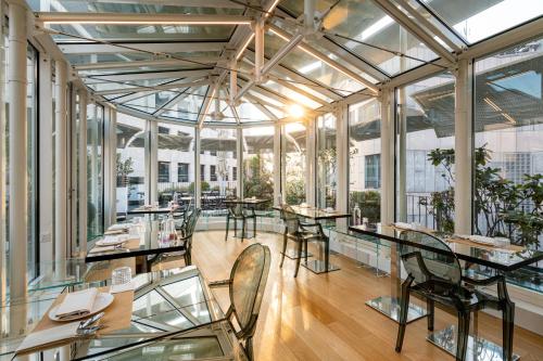 a dining room with tables and chairs and windows at The Street Milano Duomo | a Design Boutique Hotel in Milan