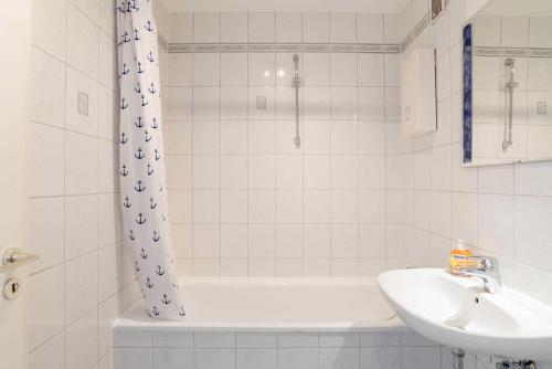 een badkamer met een bad, een wastafel en een douche bij Ferienwohnung Backbord in Schilksee