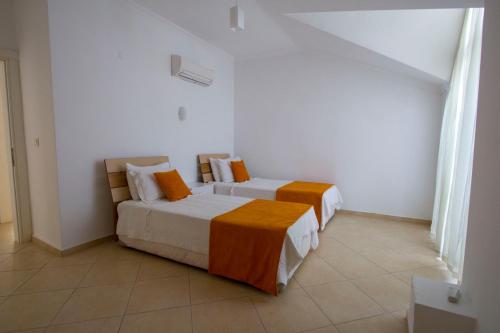 two beds in a room with white and orange at Infinity Olympia Apartments in Oludeniz