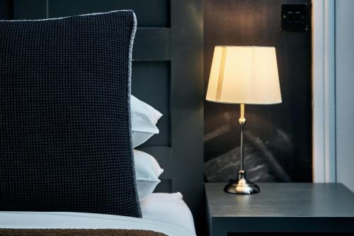 a bed with a lamp on a table with a pillow at The Brown's Hotel in Laugharne