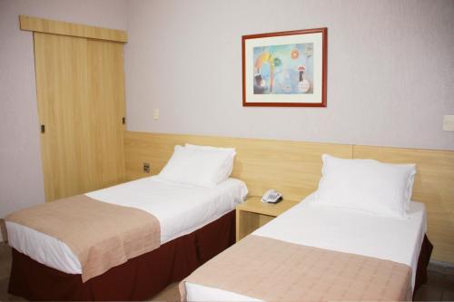 a hotel room with two beds and a picture on the wall at Hotel Foz do Iguaçu in Foz do Iguaçu