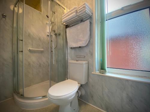 a bathroom with a toilet and a glass shower at Cumbria Guest House in Lytham St Annes