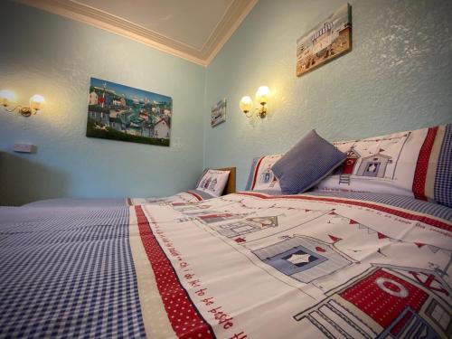 a bedroom with a bed with a red and white comforter at Cumbria Guest House in Lytham St Annes