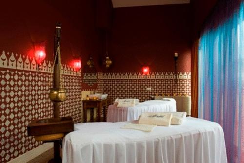 a room with two beds with white sheets and red lights at Afrodyta SPA & Wellness Resort in Ośno Lubuskie