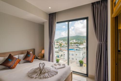 a bedroom with a bed and a large window at Nipola Hotel - Chợ Đêm Dương Đông Phú Quốc in Phú Quốc