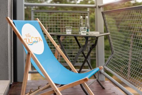 a blue chair sitting next to a table on a porch at Hotel Willa Złota in Karwia