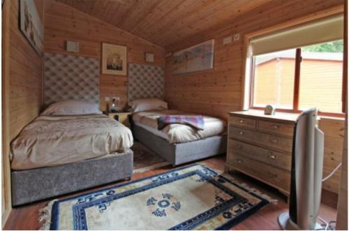 a bedroom with two beds and a dresser and a window at Astbury Falls Luxury Retreats in Eardington