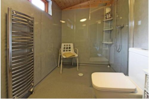 a bathroom with a shower and a toilet and a chair at Astbury Falls Luxury Retreats in Eardington