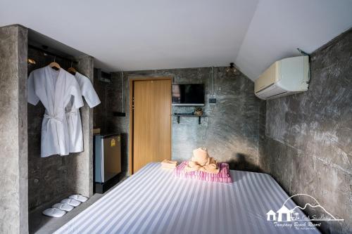 Zimmer mit einem Bett und einem weißen Bademantel an der Wand in der Unterkunft Sichang Marina Resort in Ban Tha Thewawong