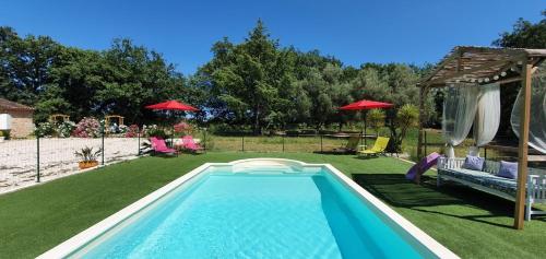 uma piscina num quintal com cadeiras e guarda-sóis em Au Charme de Pépiole em Six-Fours-les-Plages