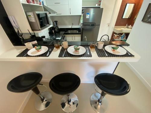 un mostrador de cocina con 2 taburetes y platos de comida en Lindo apto em Arraial do Cabo condomínio Golden Lake, en Arraial do Cabo
