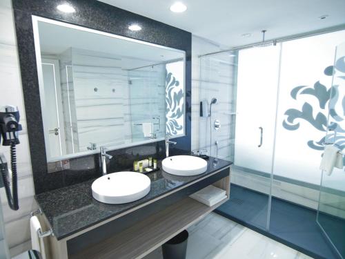 a bathroom with two sinks and a large mirror at Hotel Riu Palace Meloneras in Maspalomas