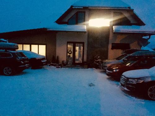 a house with cars parked in the snow at night at RELAX PENZIÓN J&L in Pavčina Lehota