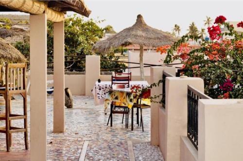 a patio with a table and chairs and an umbrella at CHAMBRES CLIMATISÉES EN VILLE in Saint-Louis