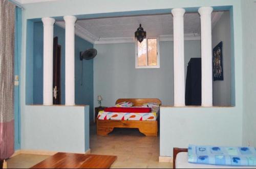 a bedroom with a bed with white columns at CHAMBRES CLIMATISÉES EN VILLE in Saint-Louis