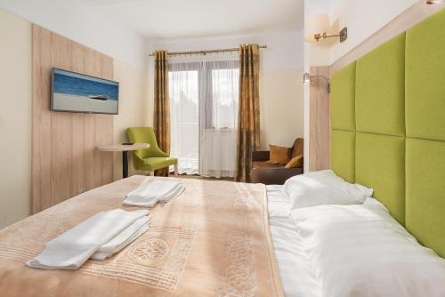 a bedroom with a large bed with two towels on it at Hotel Willa Złota in Karwia