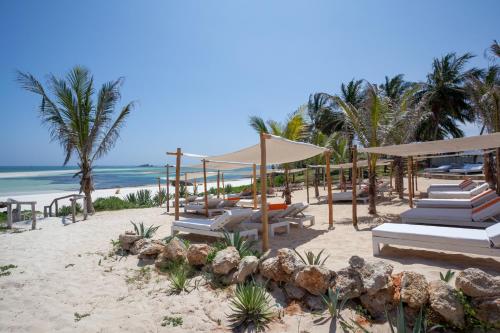 a beach with chairs and umbrellas and the ocean at Gecko Resort in Watamu