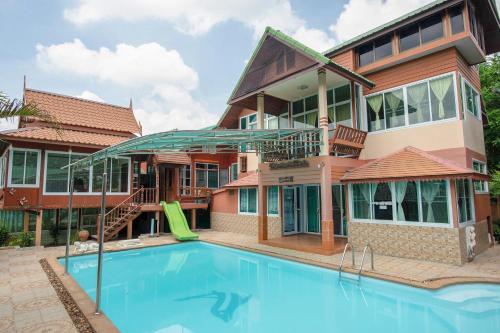 a house with a swimming pool in front of it at OYO 402 Raknatee Resort in Nakhon Pathom